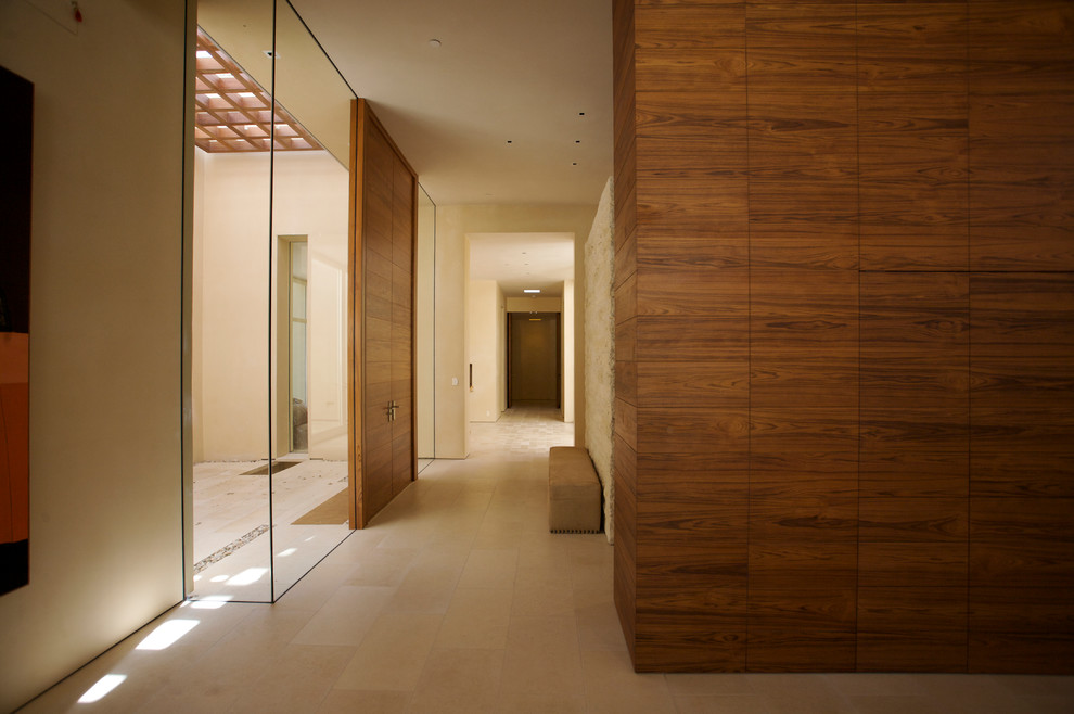 Cette image montre une grande porte d'entrée design avec un mur beige, un sol en travertin, une porte double et une porte en bois brun.