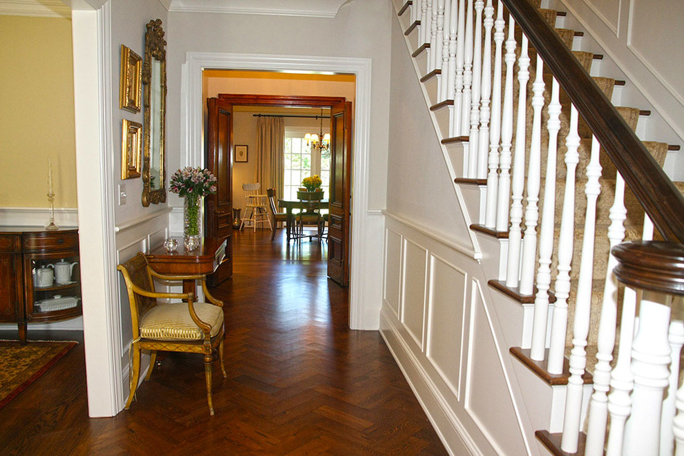 Imagen de hall clásico grande con paredes blancas, suelo de madera oscura, puerta simple, puerta de madera oscura y suelo marrón