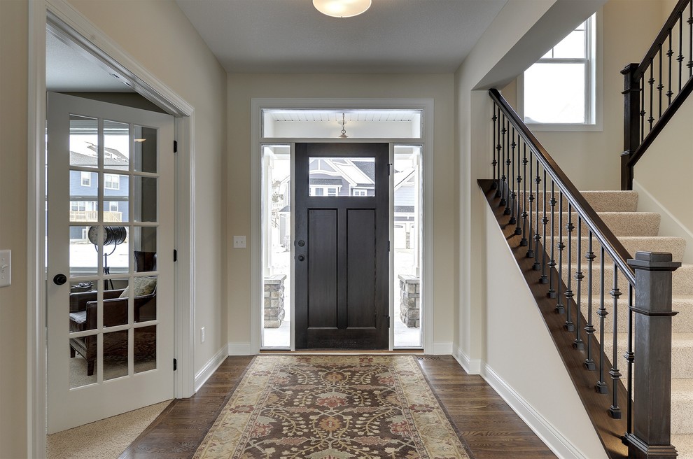 Großes Klassisches Foyer mit weißer Wandfarbe, braunem Holzboden, Einzeltür und dunkler Holzhaustür in Minneapolis