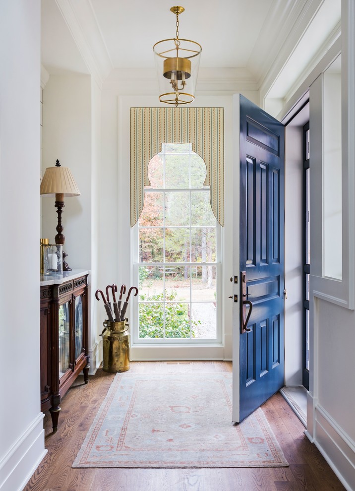 На фото: фойе среднего размера в классическом стиле с белыми стенами, темным паркетным полом, одностворчатой входной дверью, синей входной дверью и коричневым полом