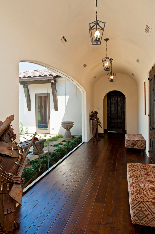 Ejemplo de hall mediterráneo con paredes beige, suelo de madera oscura y puerta de madera oscura
