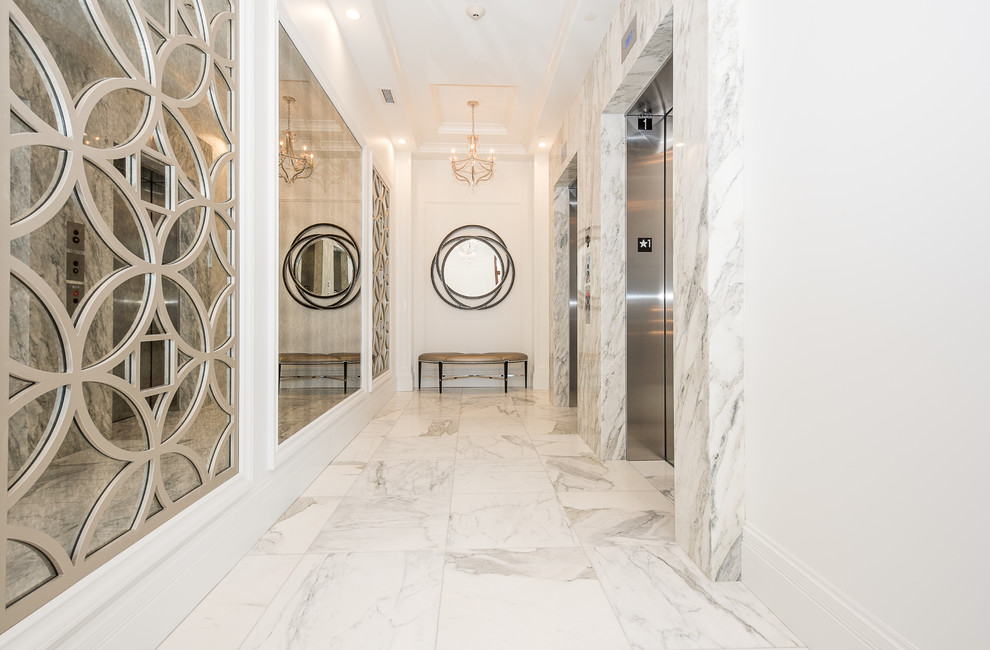 Idée de décoration pour une entrée tradition avec un mur blanc, un sol en marbre, une porte simple, une porte en bois foncé et un sol blanc.
