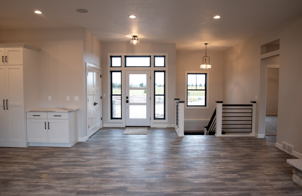 Aménagement d'une grande porte d'entrée moderne avec un mur gris, un sol en vinyl, une porte simple, une porte blanche, un sol marron et un plafond voûté.
