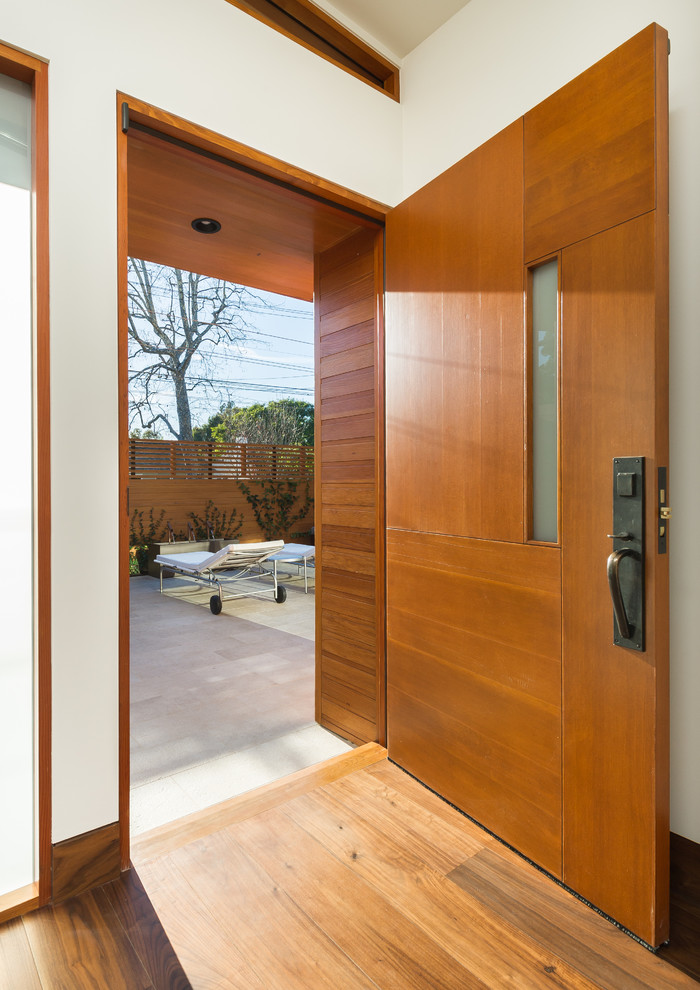 Свежая идея для дизайна: входная дверь среднего размера в стиле модернизм с белыми стенами, паркетным полом среднего тона, одностворчатой входной дверью и входной дверью из дерева среднего тона - отличное фото интерьера