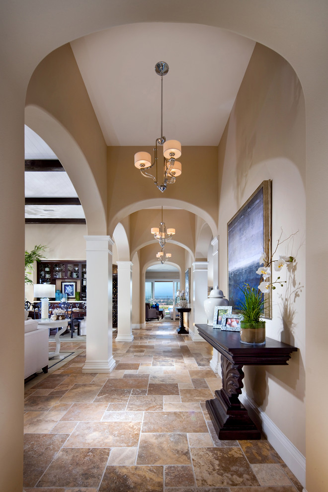 Example of a tuscan travertine floor entry hall design in San Diego with beige walls