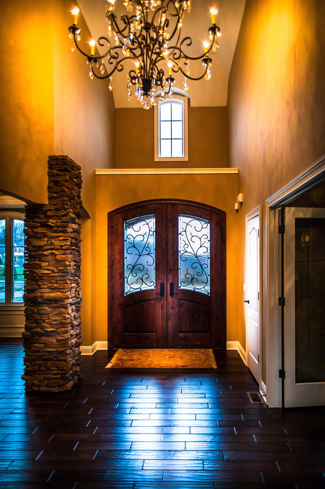 Modelo de puerta principal tradicional renovada extra grande con paredes metalizadas, suelo de madera oscura, puerta doble y puerta de madera oscura