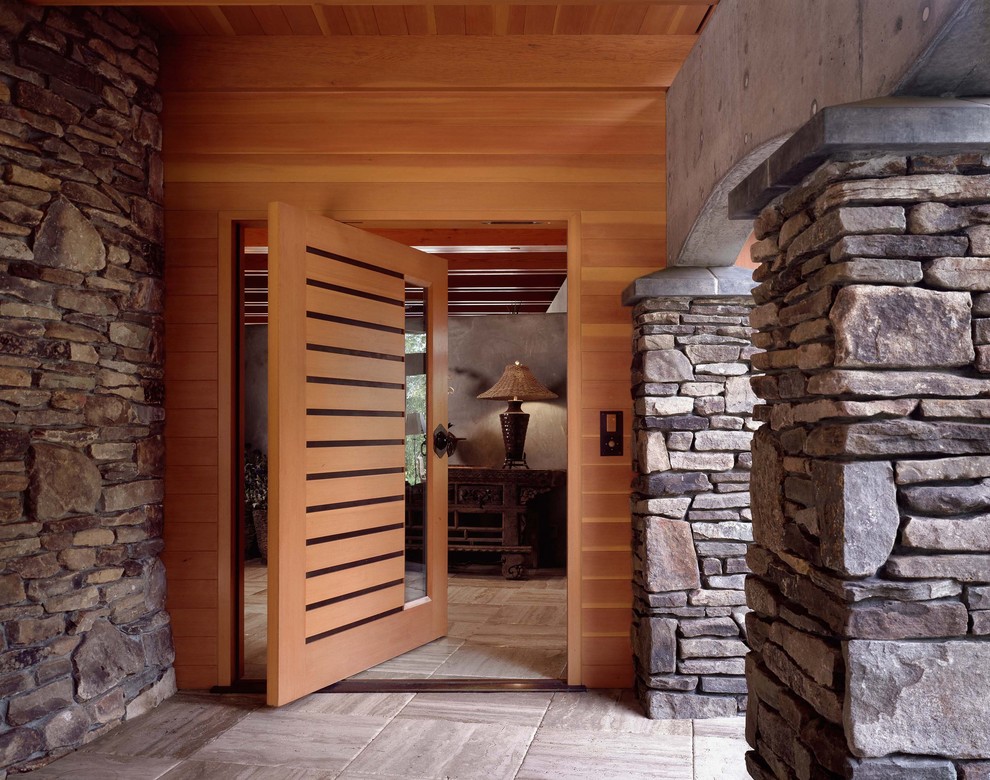 Modelo de entrada contemporánea con puerta pivotante y puerta de madera en tonos medios