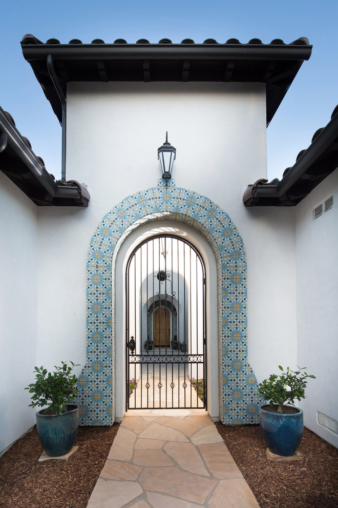 Стильный дизайн: большое фойе в средиземноморском стиле с белыми стенами, одностворчатой входной дверью и входной дверью из дерева среднего тона - последний тренд