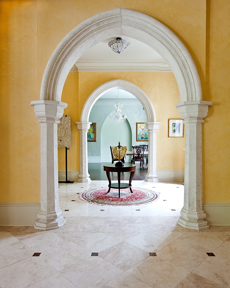 Mediterranes Foyer mit gelber Wandfarbe und Travertin in New Orleans