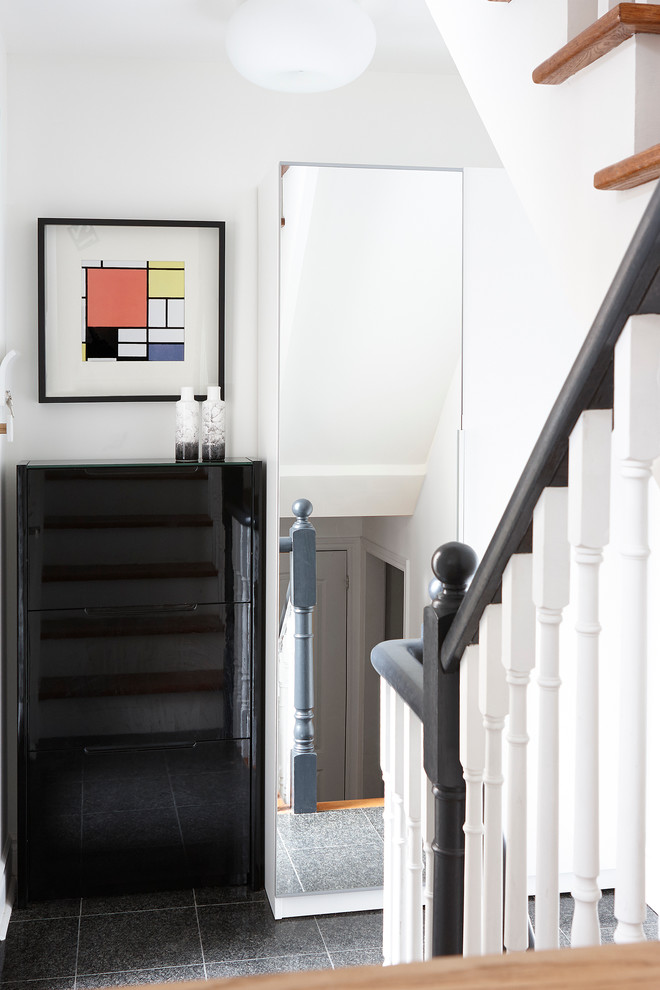 Ispirazione per un piccolo corridoio minimalista con pareti bianche, pavimento con piastrelle in ceramica, una porta singola, una porta nera e pavimento grigio