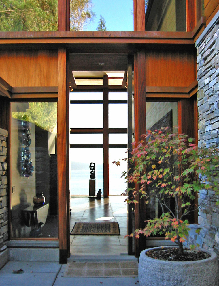 Foto di una grande porta d'ingresso contemporanea con pavimento in cemento, una porta a pivot e una porta in legno bruno