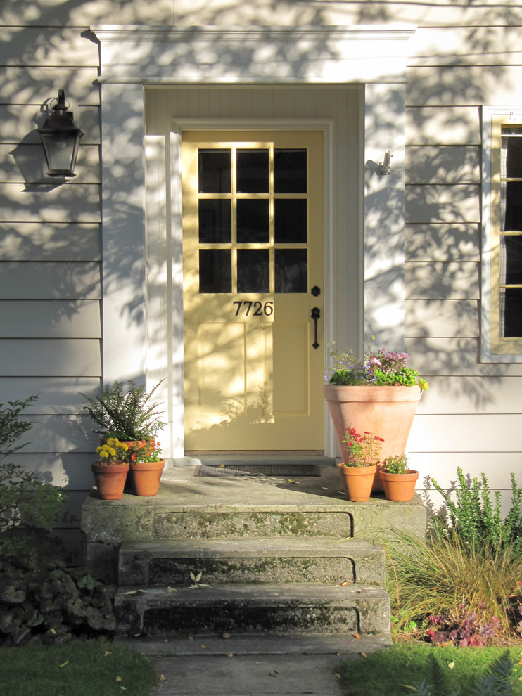 Modelo de puerta principal clásica pequeña con paredes grises, suelo de cemento, puerta simple y puerta amarilla