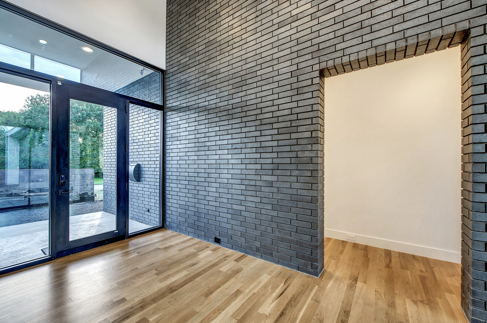 Foto de distribuidor minimalista grande con paredes blancas, suelo de madera clara, puerta simple y puerta de vidrio