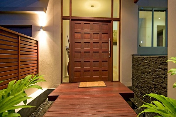 Großer Asiatischer Eingang mit beiger Wandfarbe, dunklem Holzboden, Drehtür und dunkler Holzhaustür in Sunshine Coast