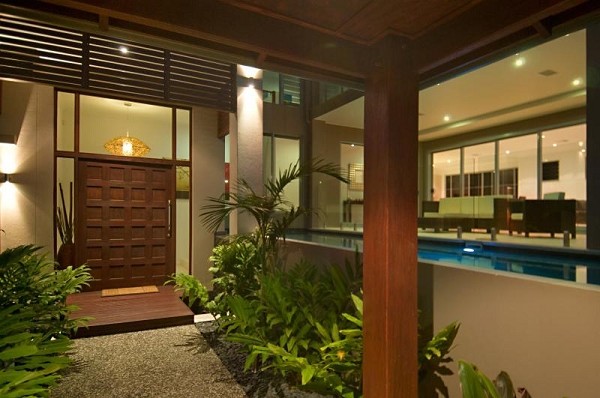 Réalisation d'une grande porte d'entrée asiatique avec un mur beige, un sol en bois brun, une porte double et une porte en bois foncé.