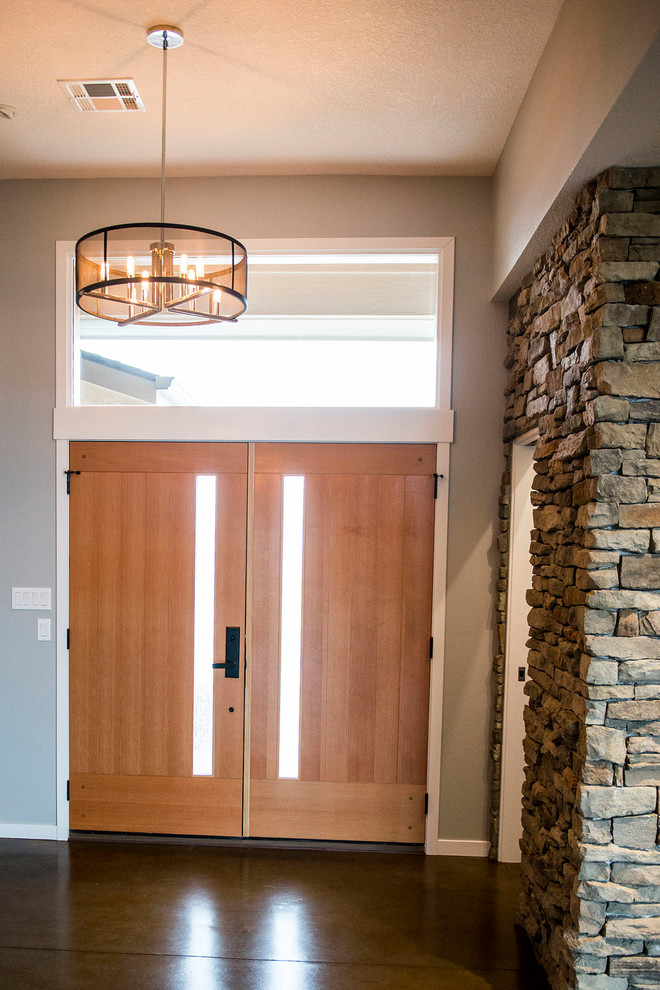 Réalisation d'une porte d'entrée vintage de taille moyenne avec un mur gris, sol en béton ciré, une porte double, une porte en bois brun et un sol marron.