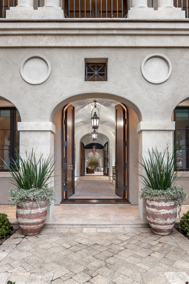 Large tuscan travertine floor entryway photo in Houston with gray walls and a dark wood front door