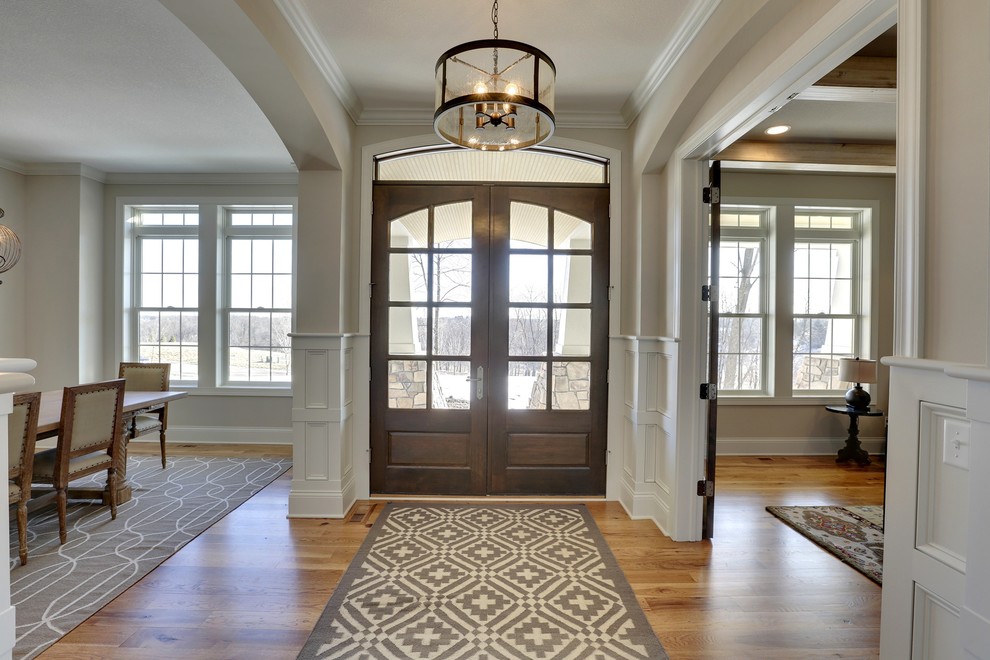 Inspiration for a large classic foyer in Minneapolis with beige walls, medium hardwood flooring, a double front door, a dark wood front door and feature lighting.