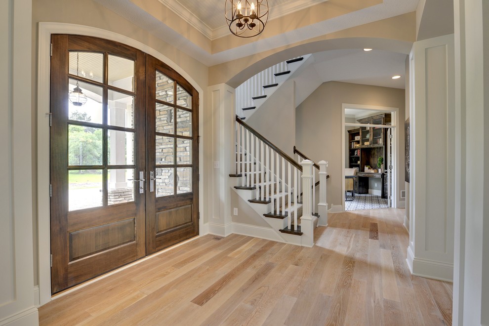 Inspiration for a large transitional light wood floor entryway remodel in Minneapolis with white walls and a medium wood front door