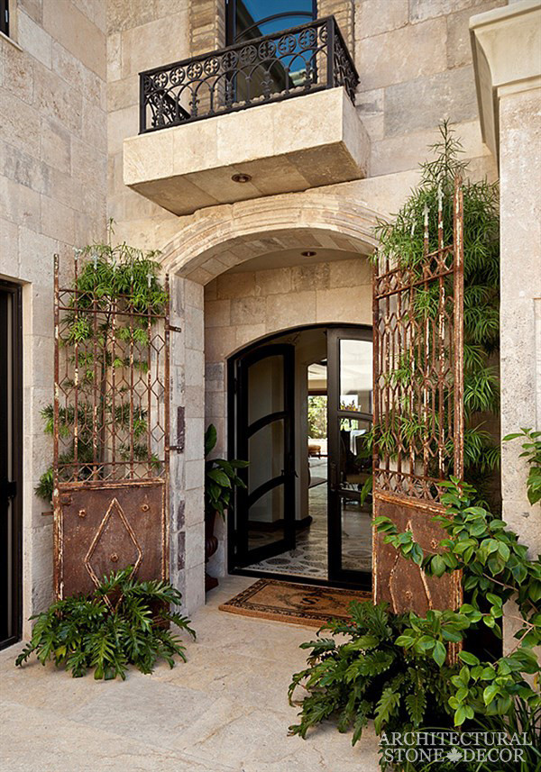 Immagine di una grande porta d'ingresso mediterranea con pareti multicolore, pavimento in pietra calcarea, una porta a due ante e una porta in vetro