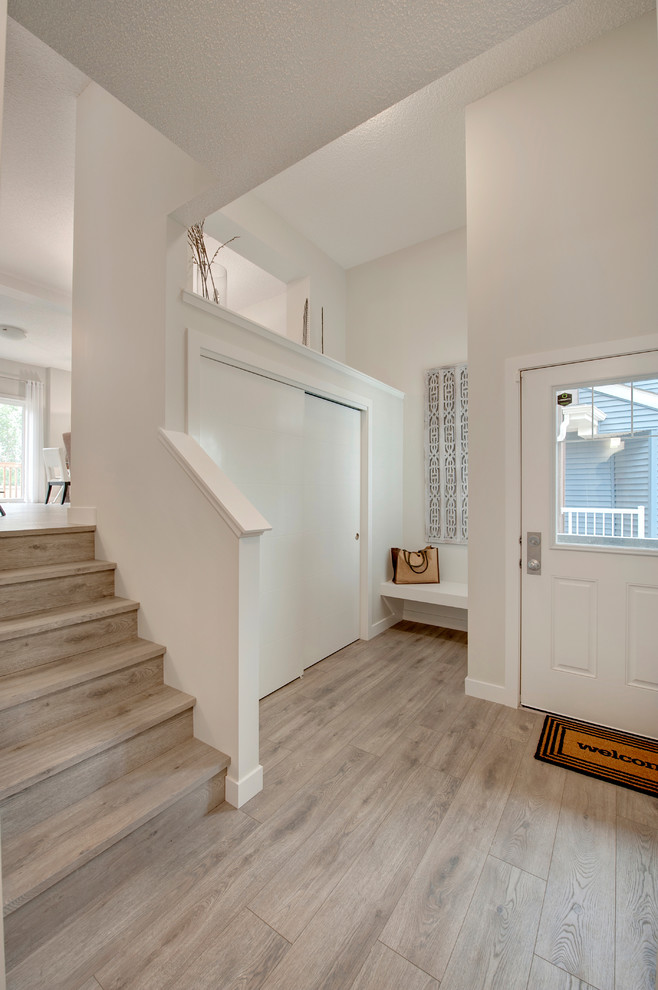 エドモントンにある低価格の小さなトランジショナルスタイルのおしゃれな玄関ドア (白い壁、ラミネートの床、白いドア、グレーの床) の写真