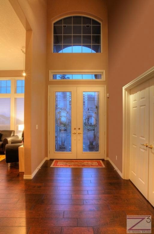 Idee per un ingresso tradizionale di medie dimensioni con pareti marroni, parquet scuro, una porta a due ante e una porta in vetro