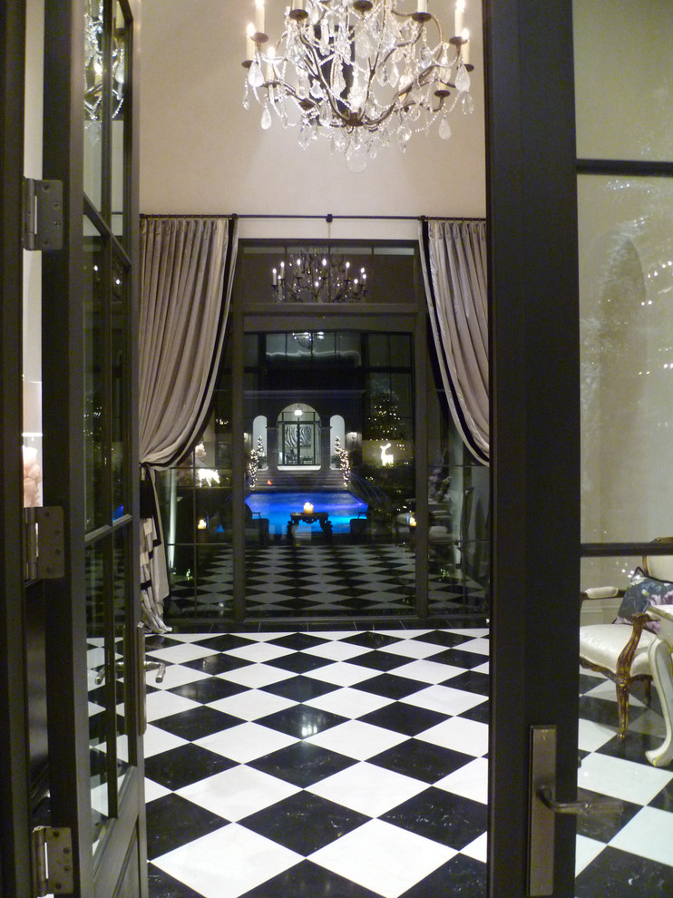 Aménagement d'un grand hall d'entrée classique avec un mur beige, un sol en marbre, une porte double et une porte noire.