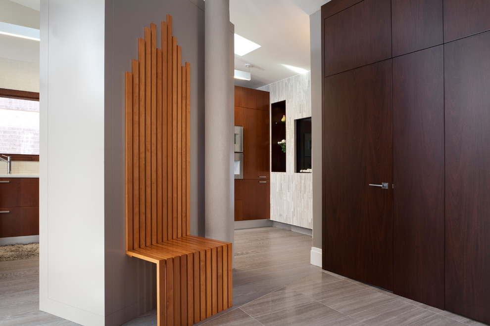 Immagine di un corridoio minimalista di medie dimensioni con pareti grigie, pavimento in gres porcellanato, una porta singola e una porta in legno scuro