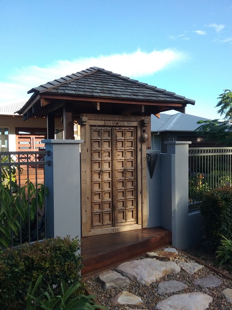 Diseño de entrada exótica de tamaño medio con paredes grises, suelo de madera en tonos medios y puerta de madera en tonos medios