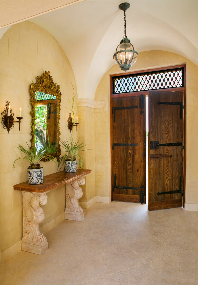 マイアミにある高級な中くらいな地中海スタイルのおしゃれな玄関ホール (ベージュの壁、磁器タイルの床、木目調のドア、ベージュの床) の写真