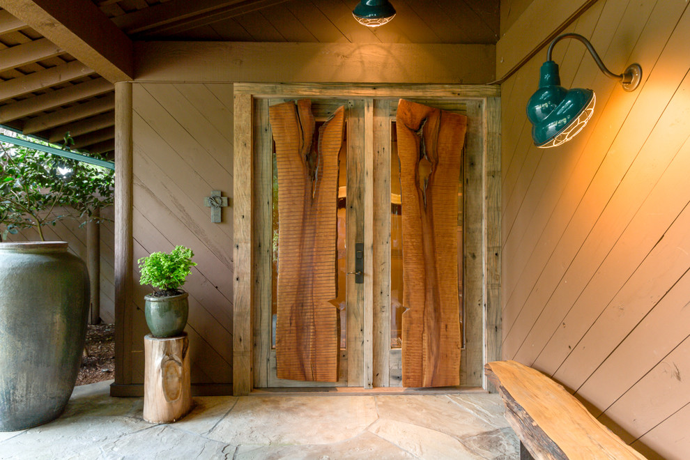 Ejemplo de puerta principal rural con paredes marrones, puerta doble y puerta de madera en tonos medios