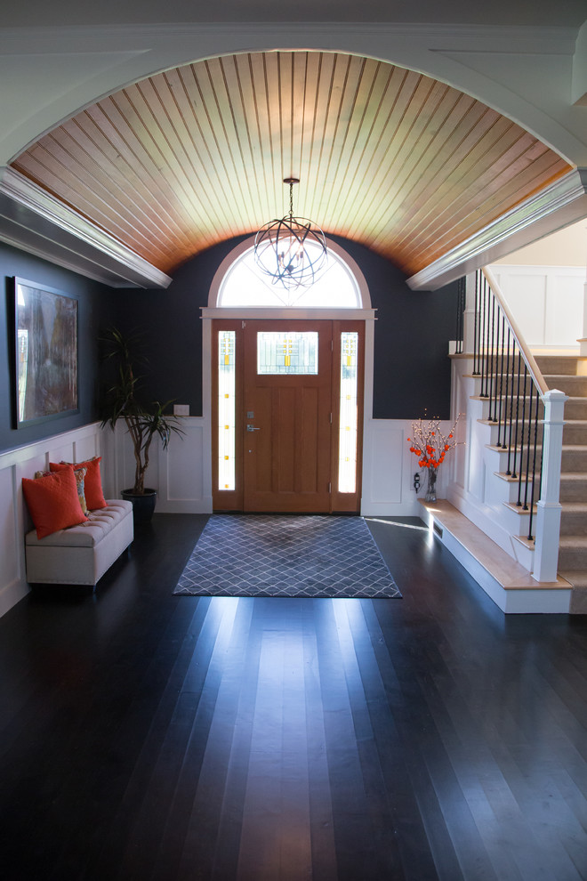 Cette image montre un très grand hall d'entrée craftsman avec un mur gris, parquet foncé, une porte simple et une porte en bois brun.