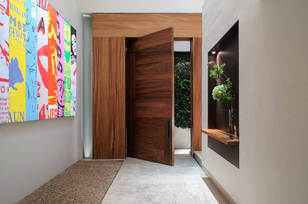 Diseño de puerta principal contemporánea grande con paredes blancas, suelo de mármol, puerta pivotante y puerta de madera en tonos medios