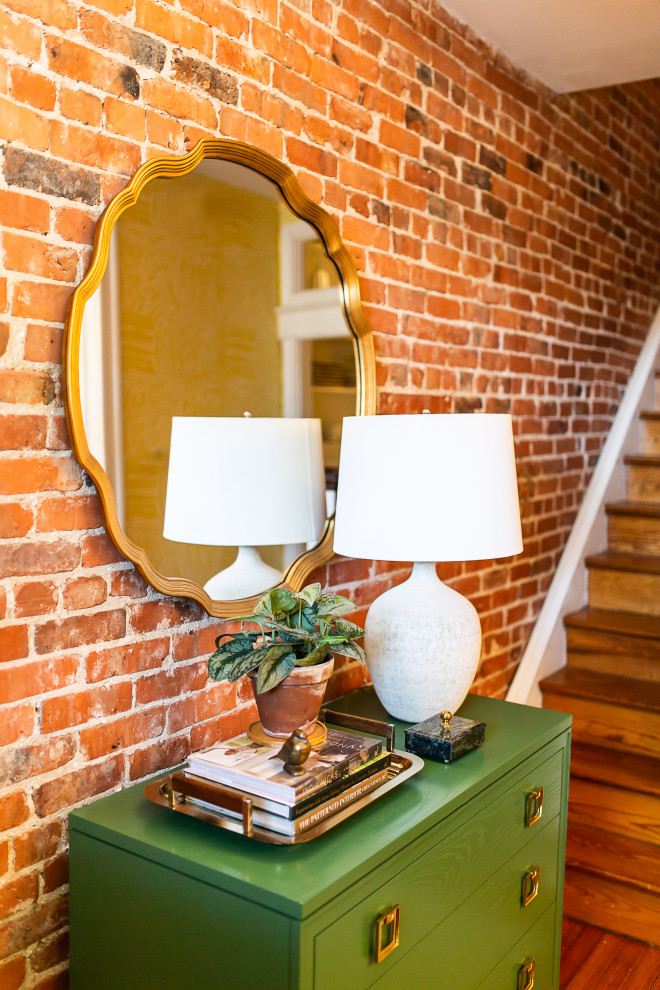 Photo of a small eclectic foyer in DC Metro with red walls, medium hardwood flooring, a single front door, brown floors and brick walls.