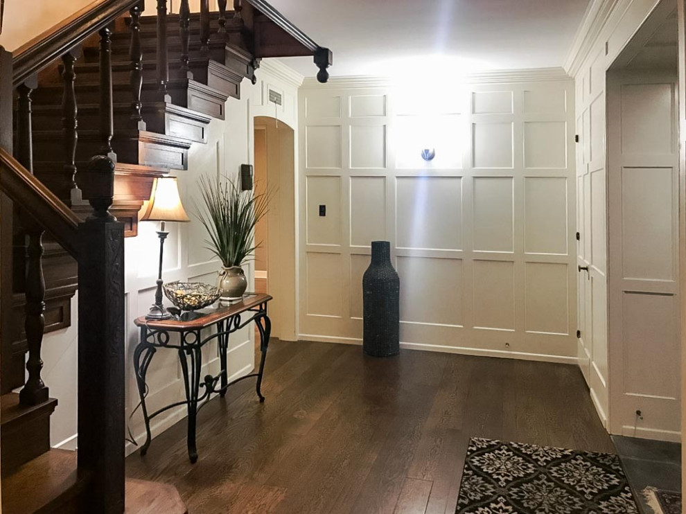 クリーブランドにあるトラディショナルスタイルのおしゃれな玄関ロビー (白い壁、濃色無垢フローリング、濃色木目調のドア、茶色い床、羽目板の壁) の写真