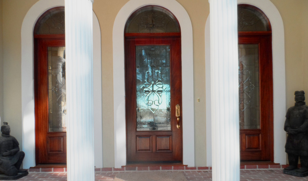 Imagen de puerta principal tradicional grande con paredes amarillas, suelo de ladrillo, puerta simple y puerta de madera en tonos medios