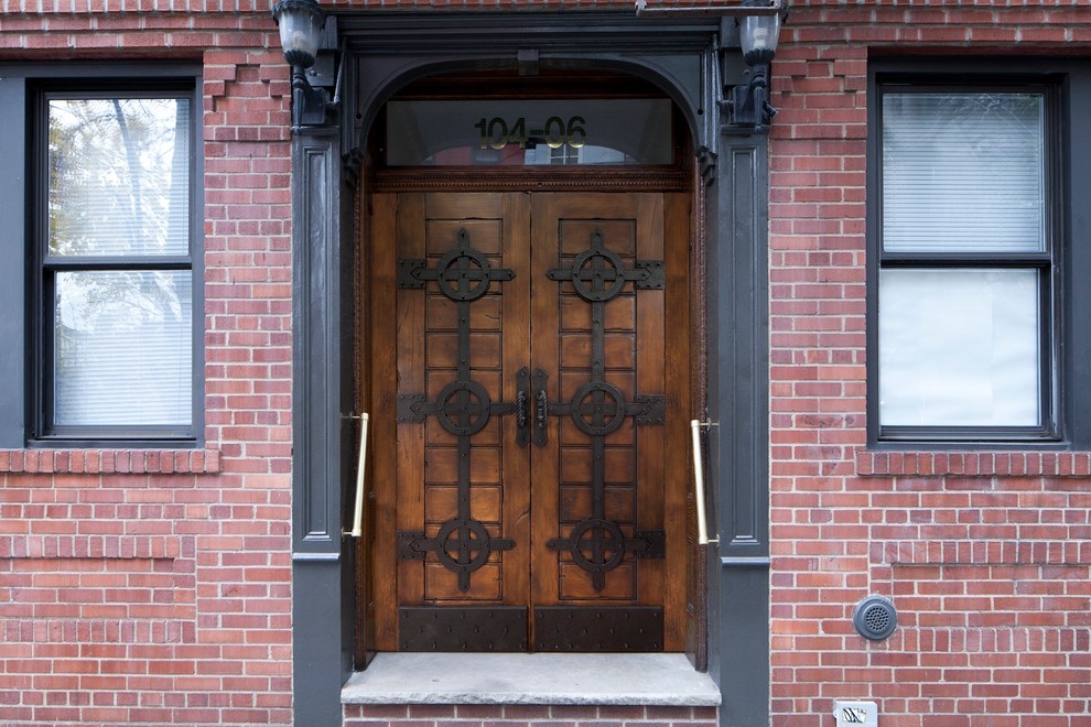 Esempio di una porta d'ingresso di medie dimensioni con pareti rosse, pavimento in cemento, una porta a due ante, una porta in legno bruno e pavimento grigio
