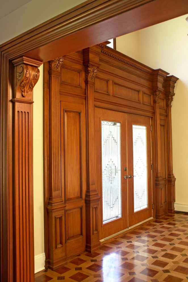 Exempel på en stor klassisk ingång och ytterdörr, med gula väggar, laminatgolv, en dubbeldörr, mellanmörk trädörr och flerfärgat golv