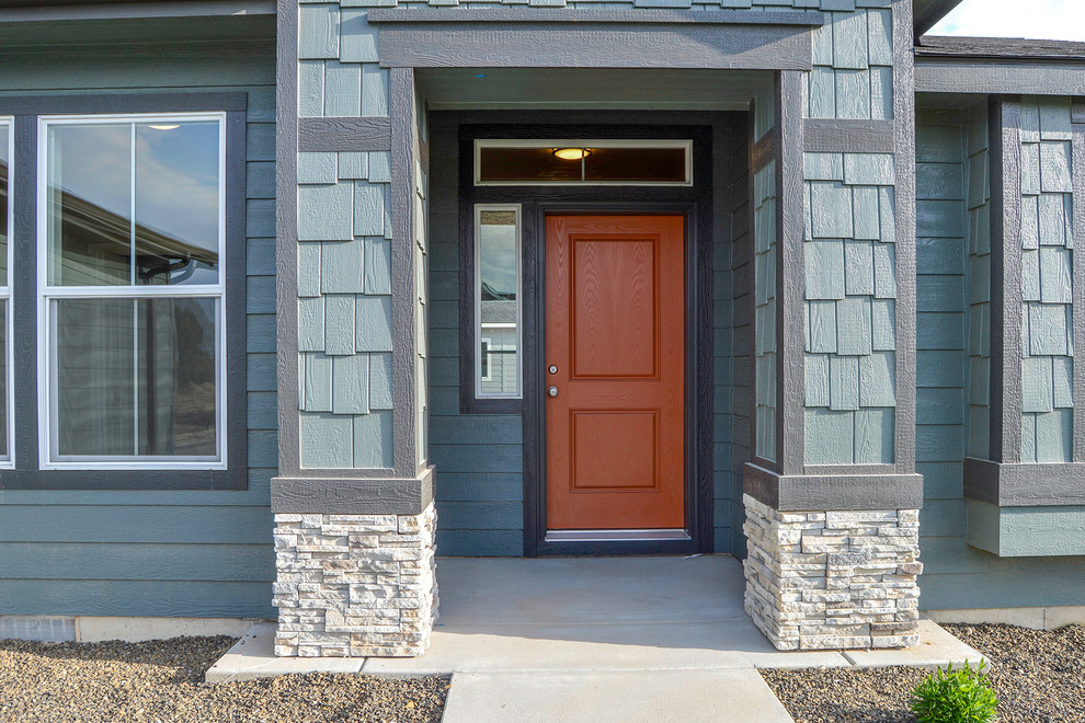 ボイシにあるトランジショナルスタイルのおしゃれな玄関ドア (青い壁、コンクリートの床、赤いドア) の写真