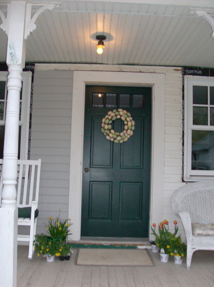 Réalisation d'une porte d'entrée champêtre de taille moyenne avec un mur beige, un sol en bois brun, une porte simple et une porte verte.