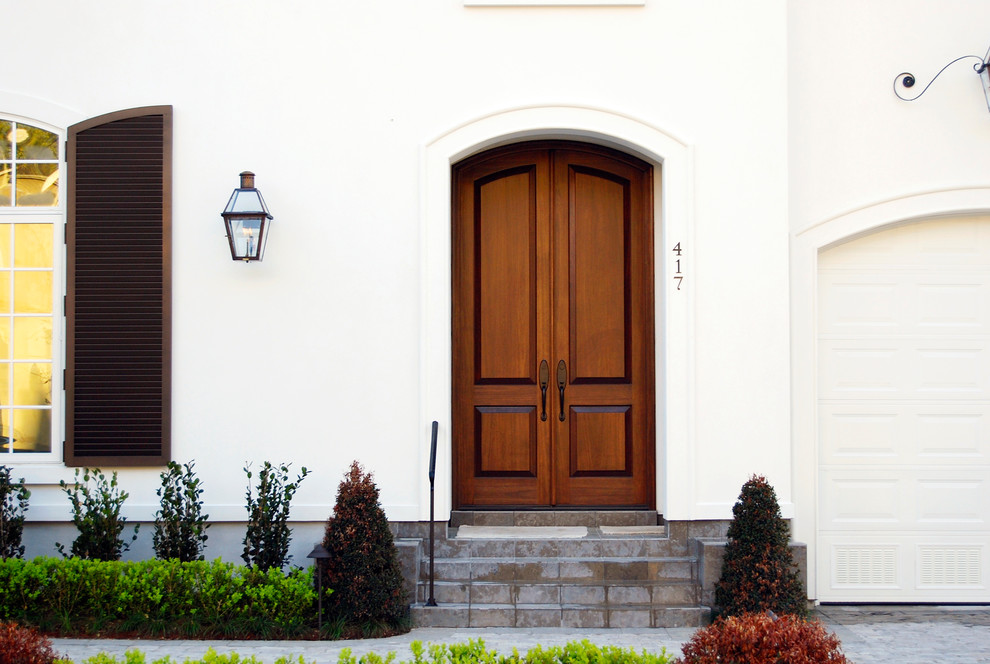 Imagen de puerta principal clásica grande con paredes blancas, puerta doble y puerta de madera en tonos medios