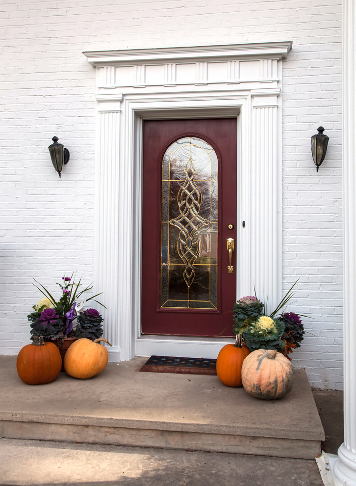 Réalisation d'une petite porte d'entrée tradition avec un mur blanc, sol en béton ciré, une porte simple et une porte rouge.