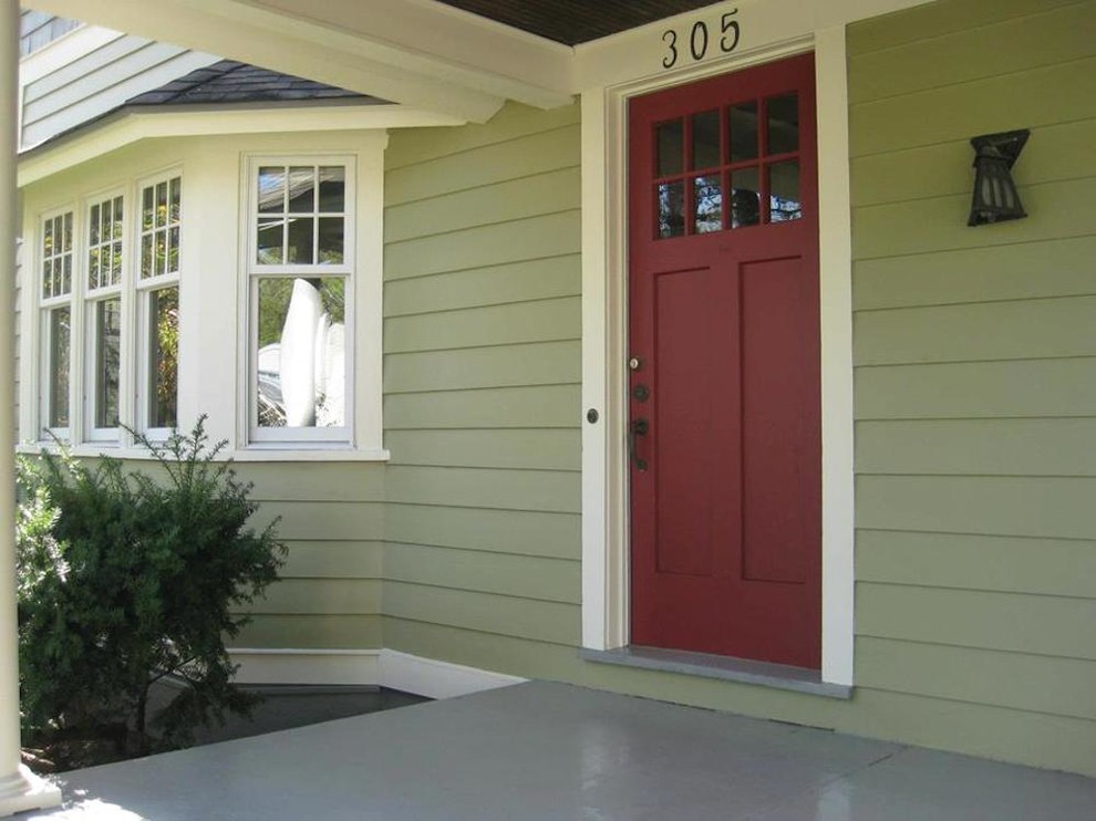 Стильный дизайн: входная дверь с зелеными стенами, бетонным полом, одностворчатой входной дверью и красной входной дверью - последний тренд