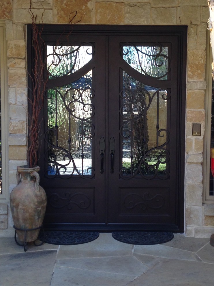 Cette image montre une grande porte d'entrée traditionnelle avec un mur multicolore, une porte double et une porte marron.