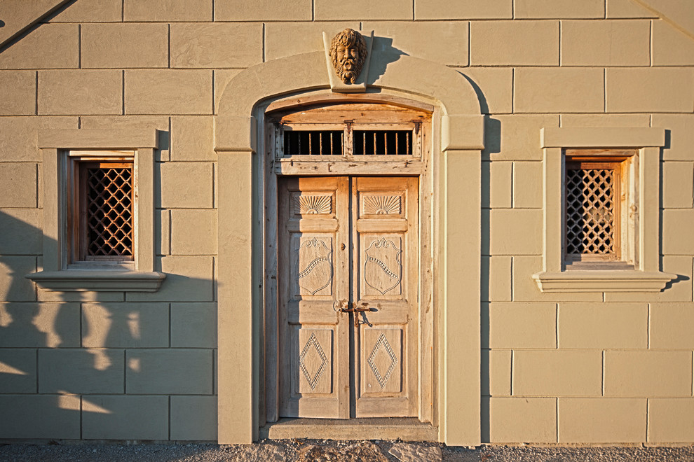 Immagine di una grande porta d'ingresso chic con pareti beige, pavimento in pietra calcarea, una porta singola e una porta marrone