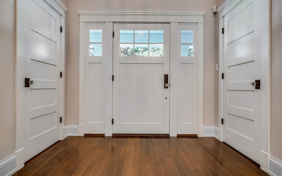 Exemple d'une entrée chic avec un sol en bois brun, une porte simple, une porte blanche et un sol marron.