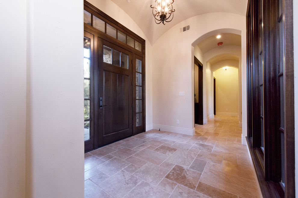サクラメントにある中くらいなトラディショナルスタイルのおしゃれな玄関ホール (ベージュの壁、トラバーチンの床、濃色木目調のドア、ベージュの床) の写真