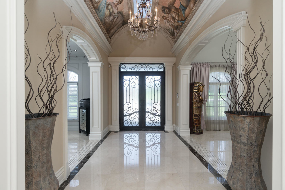 Cette image montre une entrée victorienne avec un couloir, un mur beige, une porte double, une porte en verre et un sol blanc.