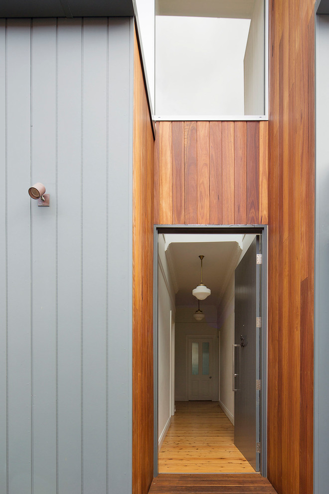 Inspiration pour une porte d'entrée design de taille moyenne avec un mur gris, un sol en bois brun, une porte simple, une porte grise et un sol marron.