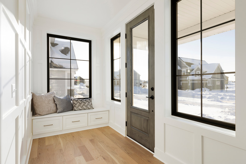 Esempio di un ingresso chic con pareti bianche, parquet chiaro, una porta singola e una porta in legno bruno